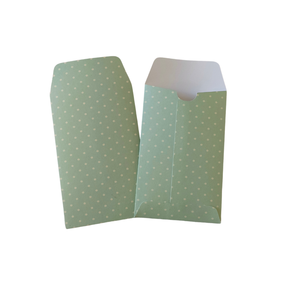 Green envelopes with white polka dots on a white background
