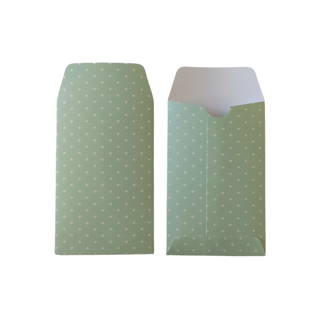 Two green envelopes with white polka dots on a white background