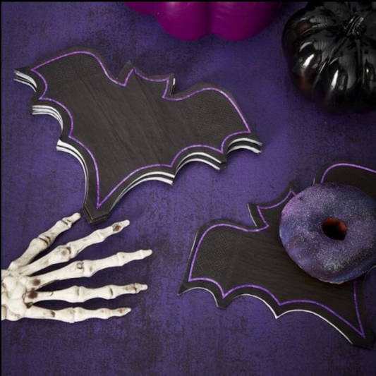 Halloween-themed decorations including bat-shaped napkins, a skeleton hand, and pumpkins on a purple background.