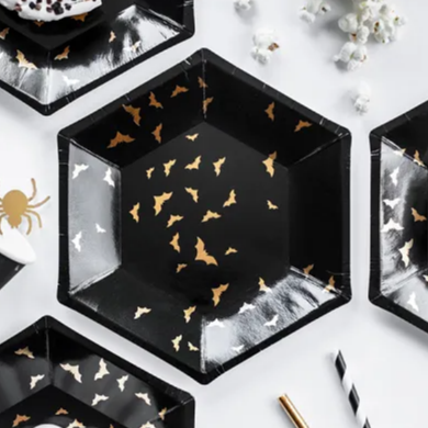 Hexagonal black plates with gold bat designs on a white surface.