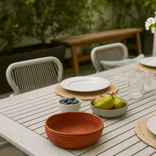 Outdoor dining table with chairs, plates, and fruit on a patio