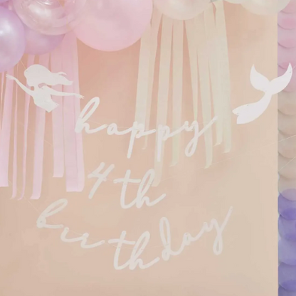 Happy birthday sign with mermaid tails and streamers on a pastel background