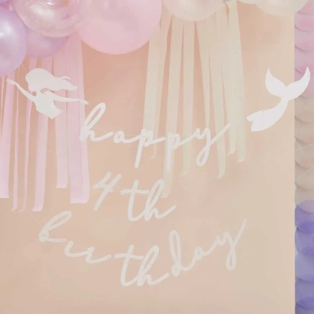 Happy birthday sign with mermaid tails and streamers on a pastel background