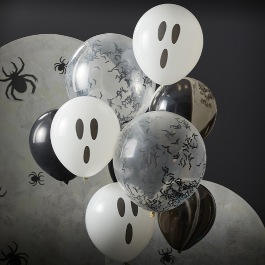 Halloween-themed balloons with ghost faces and spider patterns on a dark background