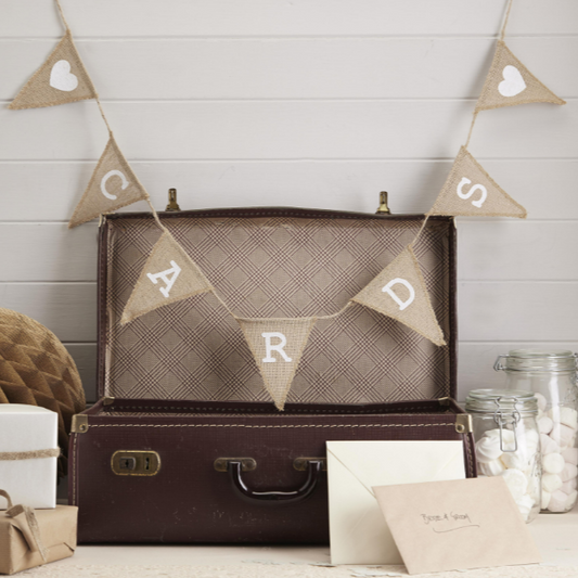 Open suitcase with 'CADETS' banner above, surrounded by decorative items on a wooden surface.