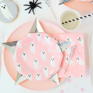 Halloween-themed table setting with pink plates, ghost decorations, and black spider.