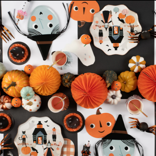 Halloween-themed plates, cookies, and decorations on a black background