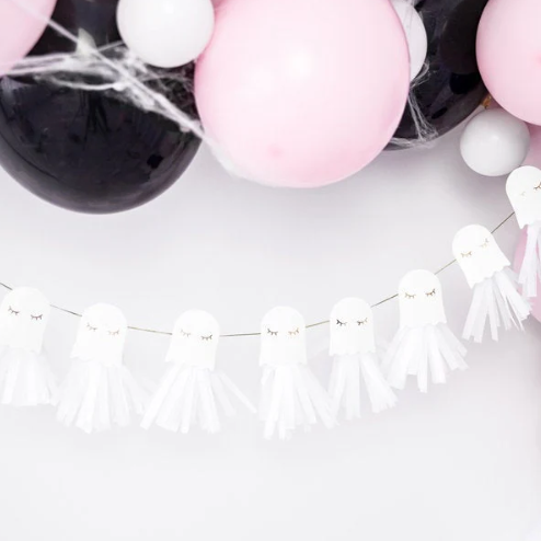 Decorative setup with pink balloons and ghost-shaped tassels on a white background