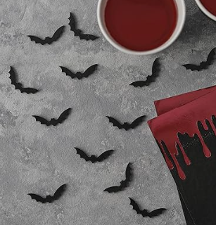 Halloween-themed decorations with black bats and red liquid on a gray surface.