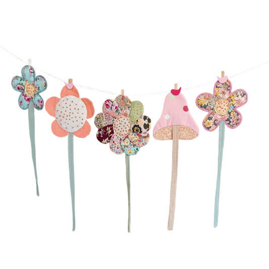 Set of colorful floral and mushroom-themed cake toppers on sticks against a white background