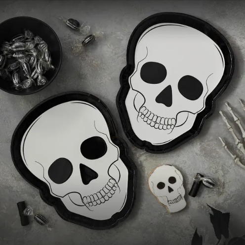 Two skull-shaped plates on a gray surface with Halloween-themed decorations.